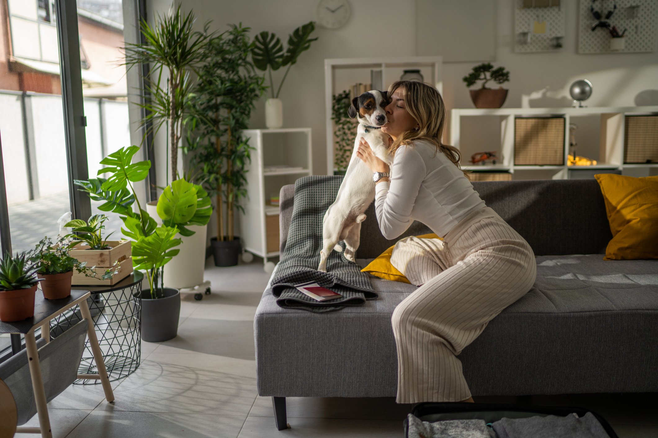 femme serrant son chien dans ses bras sur une valise en laissant son chien à la maison quand on voyage