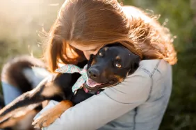 Une femme serrant dans ses bras son nouveau chien mutt noir qui vient d'être adopté.